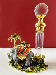 Handmade crystal perfume bottle with golden cap beside a decorative elephant figurine with red and gold blanket