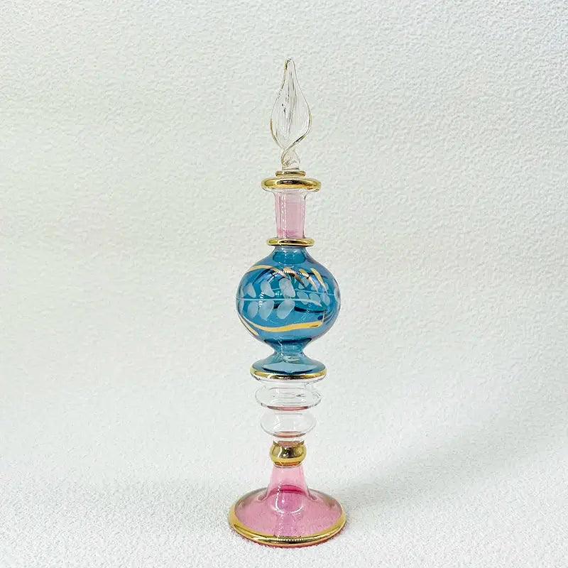 A delicate blue and pink handmade glass bottle with gold accents and a clear twisted stopper, an exquisite ornament for decor