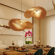 Two golden brown handmade bamboo wave pendant lights with organic design hang above the dining table