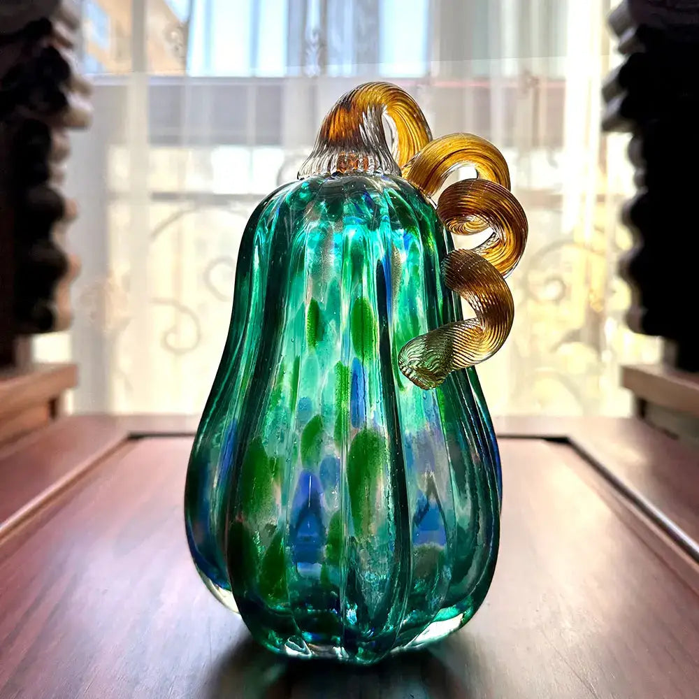 Handmade iridescent teal and green glass pumpkin figurines with swirling hues and a golden stem for living room decor