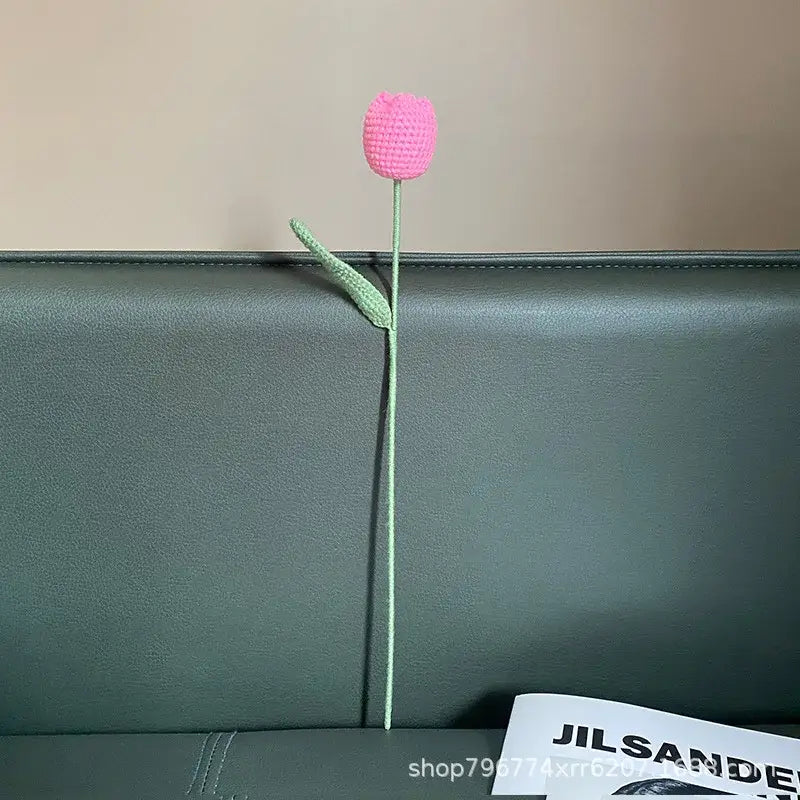 A handcrafted pink crocheted tulip with slender green stem and leaf for decorbites handmade knitted bedroom decor