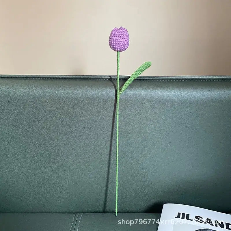 Handmade knitted crochet purple tulip with green stem resting on dark leather for decorbites handmade knitted decor