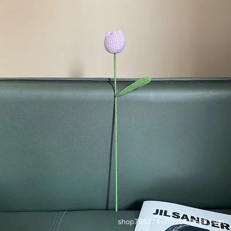 Handmade knitted crochet lavender tulip with green stem and leaf displayed on dark leather couch for decorbites decorbites handmade knitted bedroom flower decor