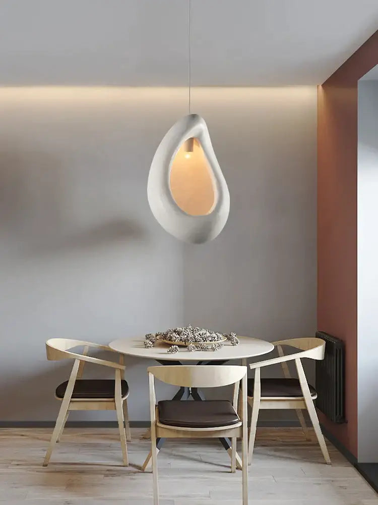 Handmade nordic designer chandelier with a matte white ceramic teardrop pendant light glowing amber for dining room decor