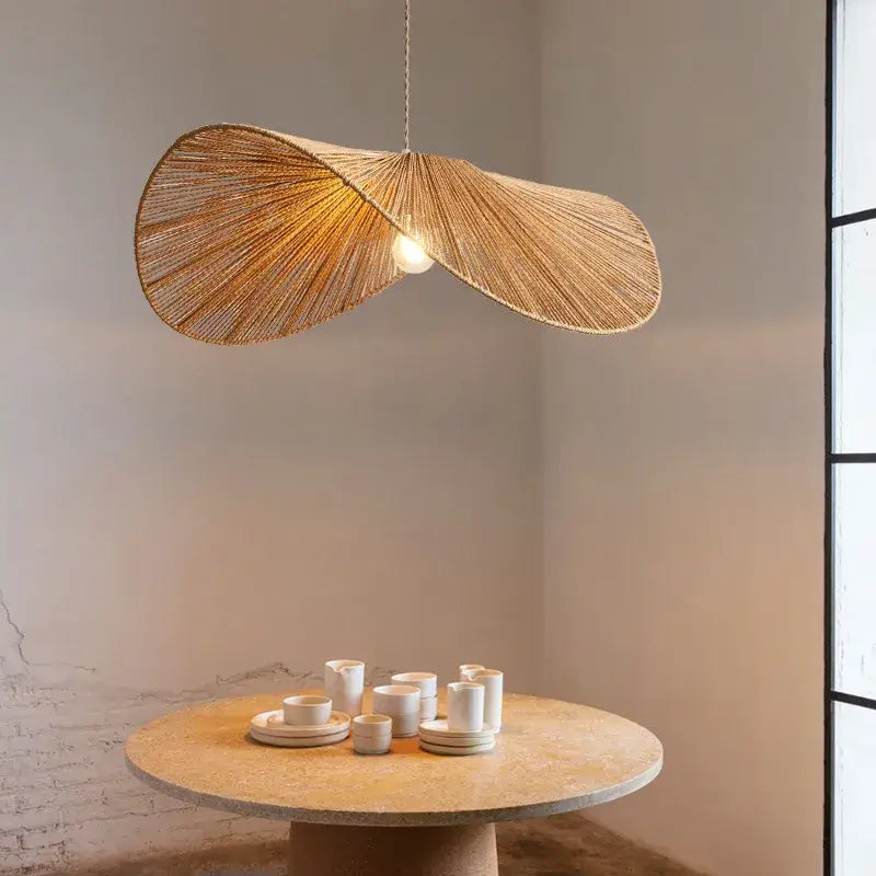 A golden-brown handmade rattan rope vertigo pendant lamp by decorbites hangs above the dining table