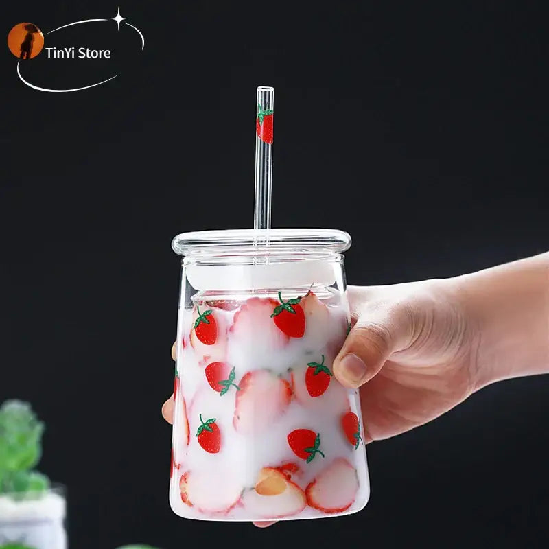 Handmade pink glass cup set with strawberry decals and matching straw filled with pink milkshake for kitchen use