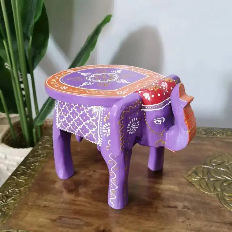 Hand-painted purple wooden elephant stool with white and gold floral patterns red accents and orange-bordered top decorbites elephant stool