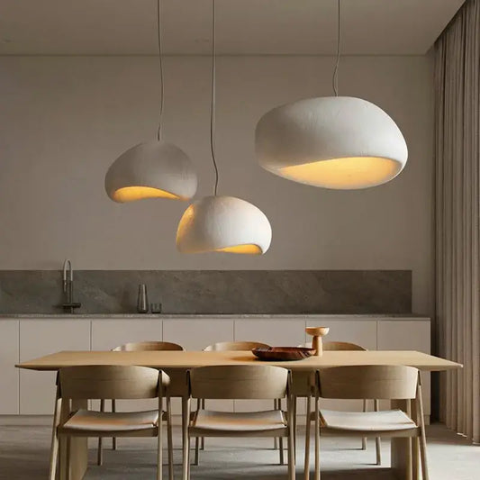Three off-white handmade wabi sabi pendant lamps with organic cloud shapes hang above a dining table decorbites lamp