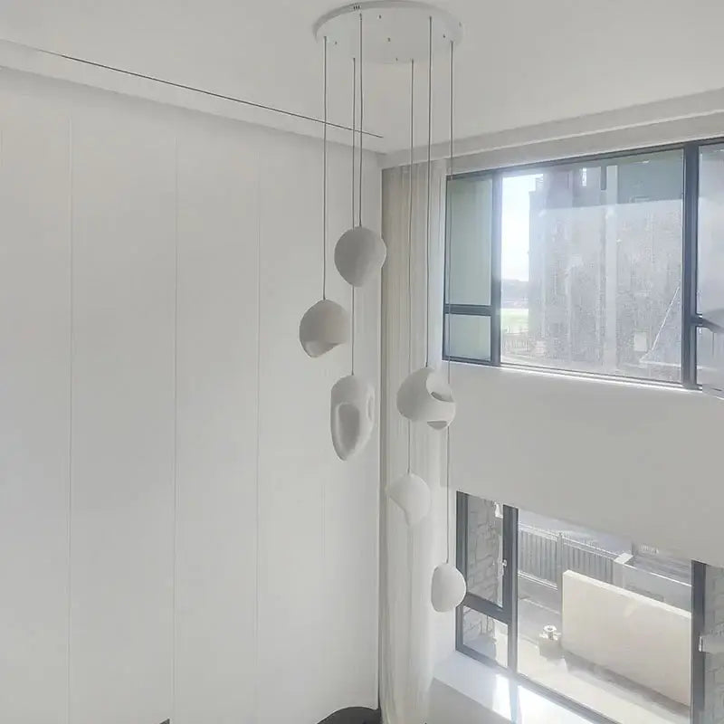 Modern white ceramic handmade wabi sabi pendant lights with organic sculptural shapes hanging from circular mount