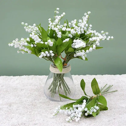 A clear glass vase with rope neck holds handmade white bellflower artificial flowers for wedding decor