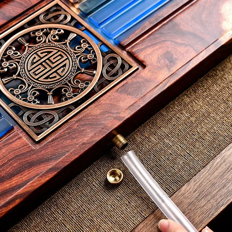 A polished dark wood tea tray with brass inlay and blue glass components for a bubble tea table