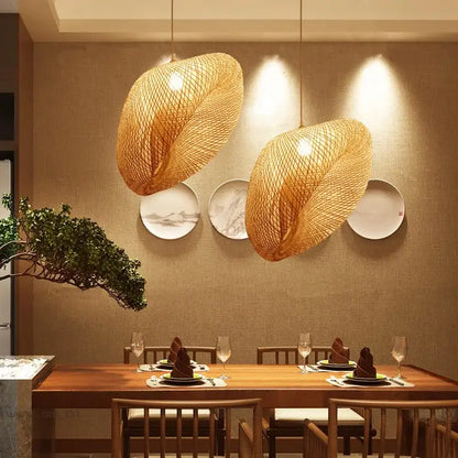 Two warm-toned woven bamboo pendant lights hanging above a wooden dining table in decorbites bamboo chandelier design