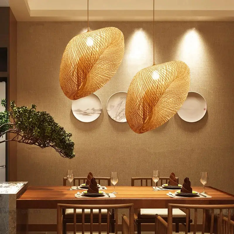 Two warm-toned woven bamboo pendant lights hanging above a wooden dining table in decorbites bamboo chandelier design