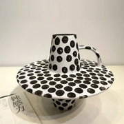 A handpainted black white dots ceramic mug and saucer set featuring white dots in a decorbites black white design