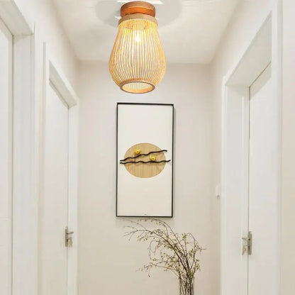 Warm-toned handwoven bamboo birdcage ceiling light with wooden top and glowing vertically slatted shade for dining room decorbites bamboo birdcage
