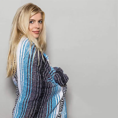 A woman draped in a decorbites handwoven mexican blanket with blue white black stripes and geometric patterns
