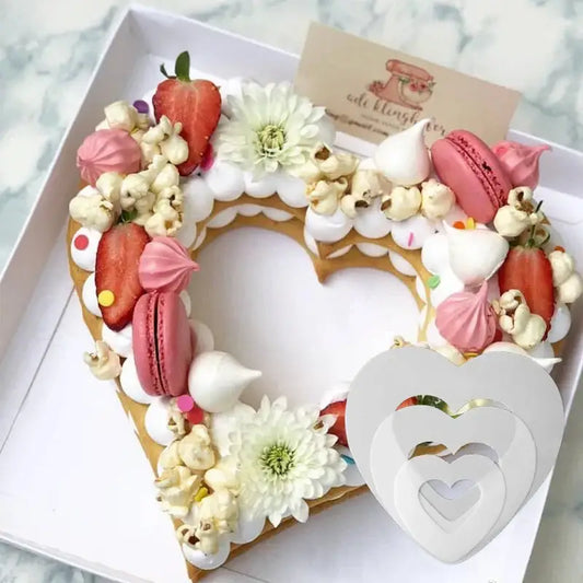 Heart cake mold showcasing a heart-shaped cake decorated with pink macarons strawberries white flowers and popcorn