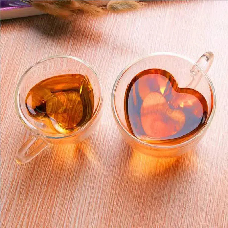 Two clear glass heart love double walled coffee mug cups filled with amber liquid for kitchen drinkware use