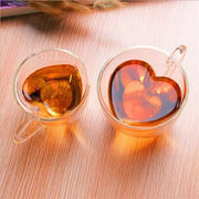Two clear amber liquid-filled heart shaped double wall glass mugs in a kitchen drinkware set