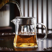 Clear glass teapot with stainless steel infuser filled with amber tea for heat resistant glass fair cup kung fu tea set