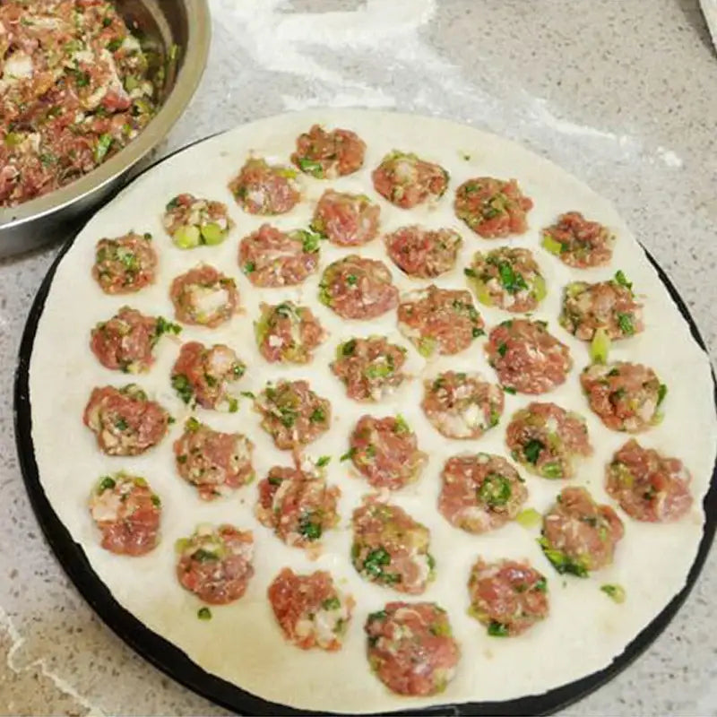 Hexagonal black aluminum dumpling maker mold with a round flat dough base filled with meat and herbs in a grid pattern