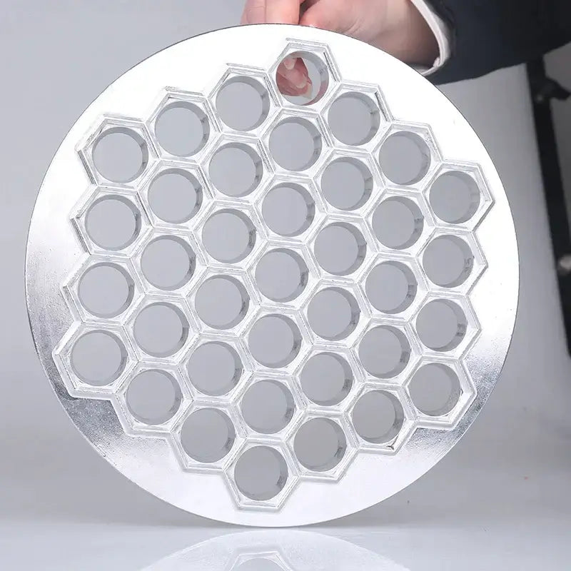Silver honeycomb-patterned aluminum dumpling maker mold with circular indentations for kitchen use