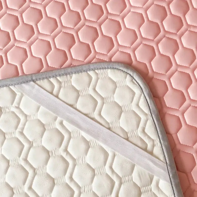 White quilted hexagonal cooling bed sheet set with silver trim on a pink textured surface for bedroom use