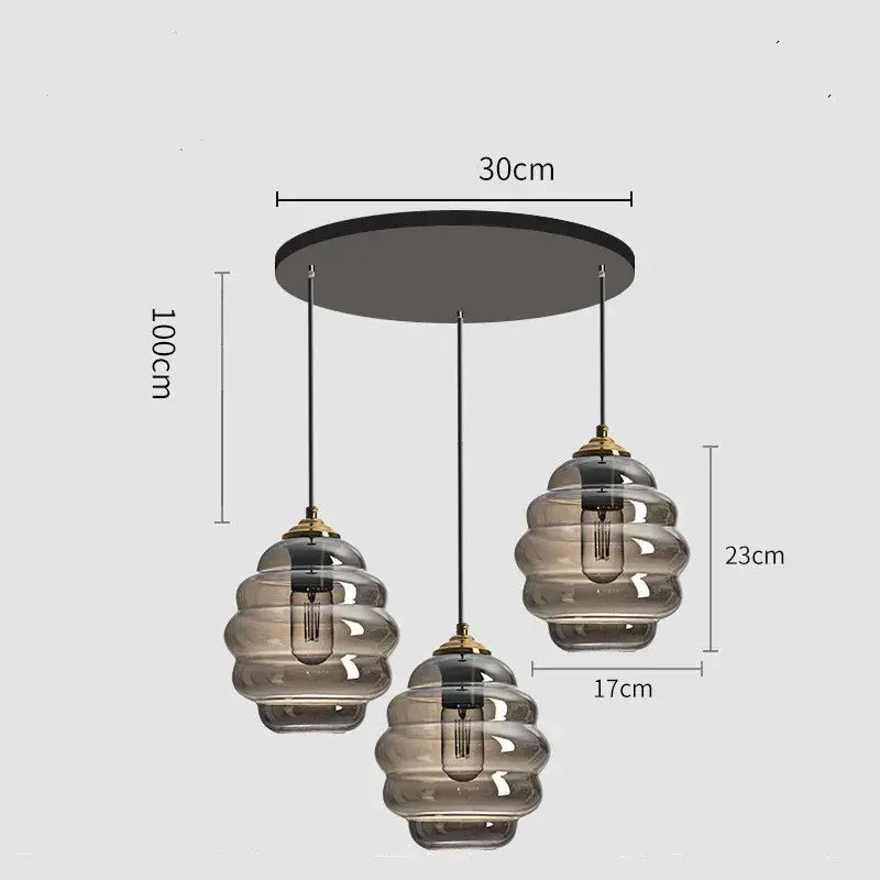 Modern three-light pendant light with smoked honeycomb amber blue and gray glass shades and brass accents for kitchen decorbites colorful glass