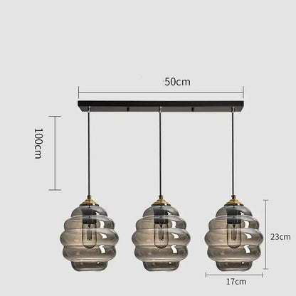 Modern three-light pendant light with smoked honeycomb amber blue and gray glass shades and brass accents for kitchen decorbites colorful glass