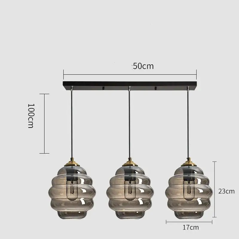 Modern three-light pendant light with smoked honeycomb amber blue and gray glass shades and brass accents for kitchen decorbites colorful glass
