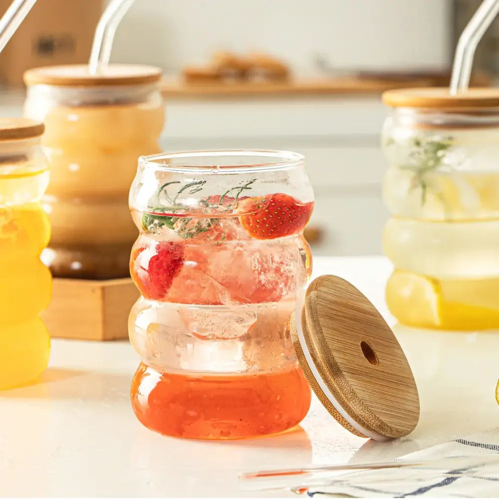 Honeycomb creative glass cup set with clear glass tumbler, bamboo lid and straw, filled with ice strawberries and herbs