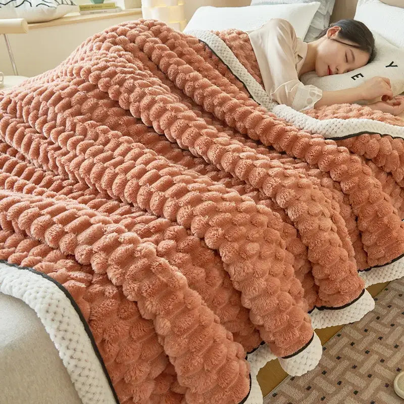 A plush peach-colored cozy coral fleece bed blanket with raised pom-pom texture and cream trim by decorbites cozy coral