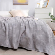 A soft light gray honeycomb waffle cotton throw blanket with textured diamond pattern draped over a bed decorbites honeycomb waffle