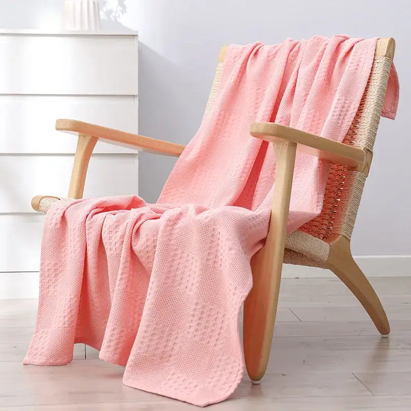 A soft pink honeycomb waffle cotton throw blanket draped over a wooden woven chair for decorbites bedroom decor