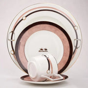 A white porcelain cup with pink and brown horsebit design and gold accents from the hermès decorbites bone china tableware set