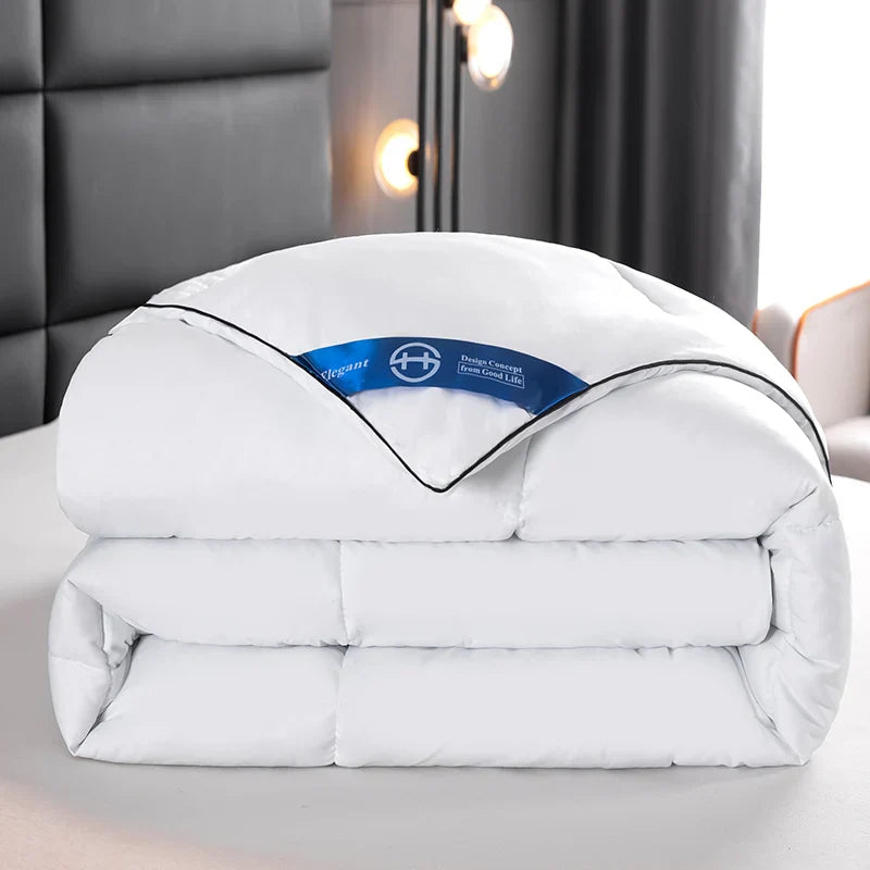 White quilted lightweight hotel style comforter with black piping and blue brand tag for queen and king beds