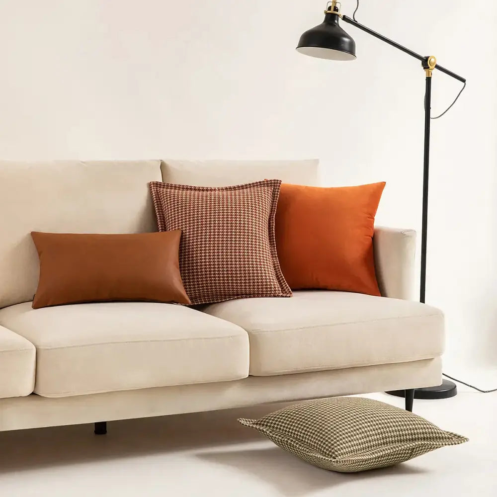 Cream-colored velvet sofa with three decorative throw pillows including a decorbites hounds tooth square cushion cover