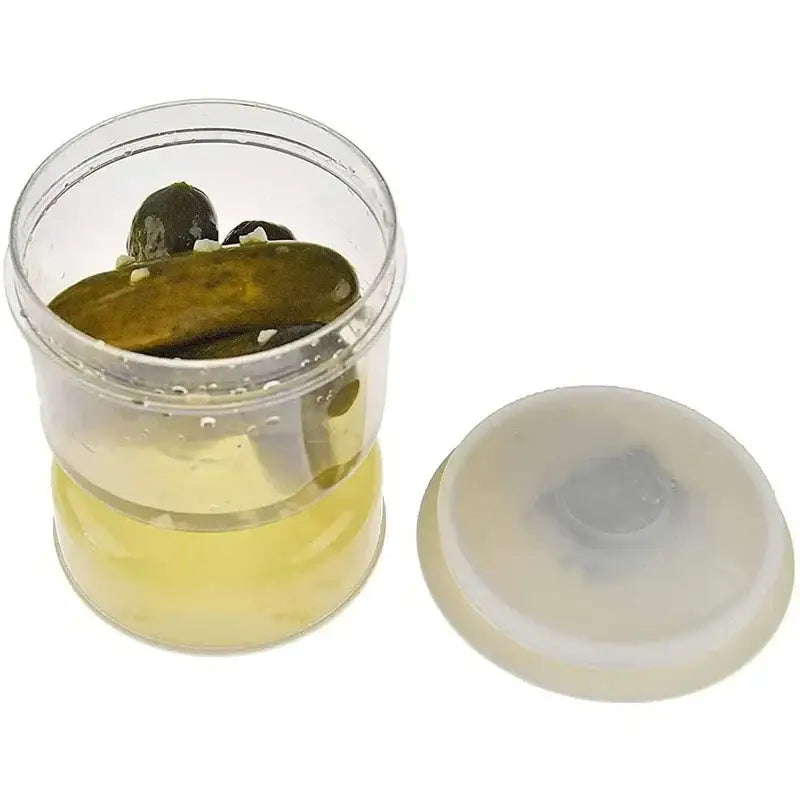 Clear plastic hourglass pickle and olive dispenser jar with matching lid containing green pickles in yellow brine