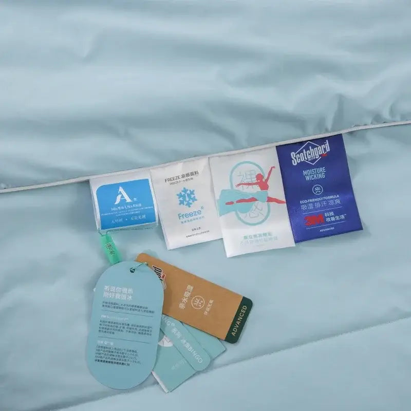 A light blue ice silk cooling blanket with multiple care tags including scotchgard moisture wicking by decorbites