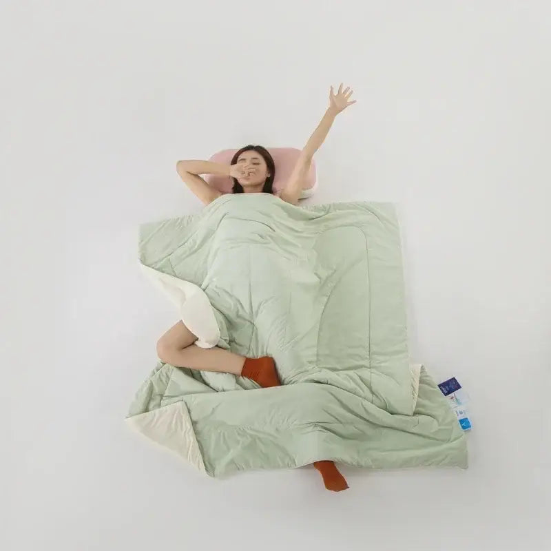A soft mint green quilted decorbites ice silk cooling blanket with cream inner lining for bedroom comfort