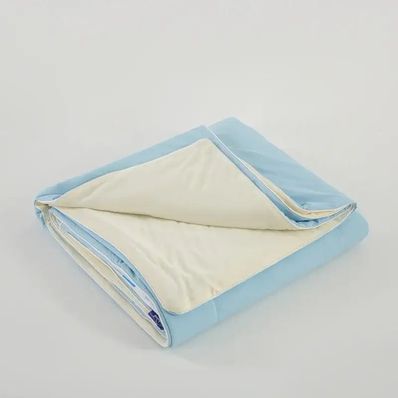A soft folded decorbites ice silk cooling blanket with light blue outer layer and creamy white inner lining