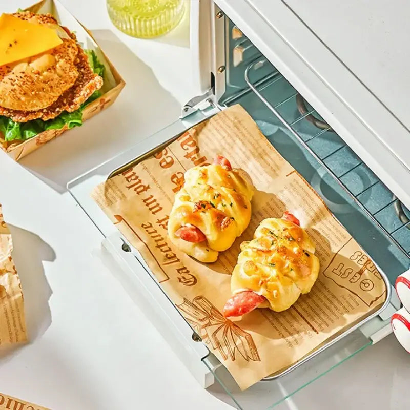Golden-brown sausage rolls on grease-resistant illustrated baking paper in a toaster oven for kitchen food wrapping