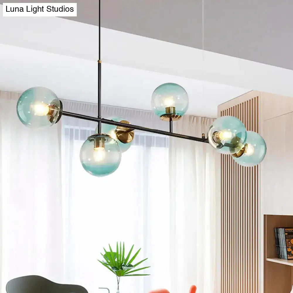 Modern teal glass globe island pendant light with brass accents and black metal frame for industrial use