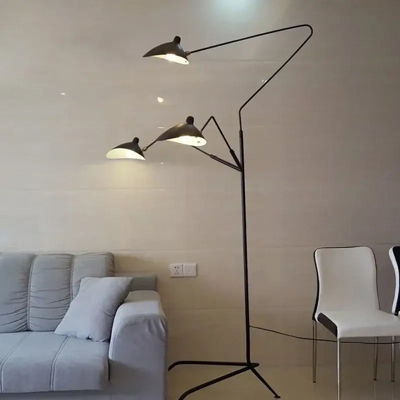 Black metal floor lamp with three adjustable spider arm shades emitting warm light for living room decorbites decor