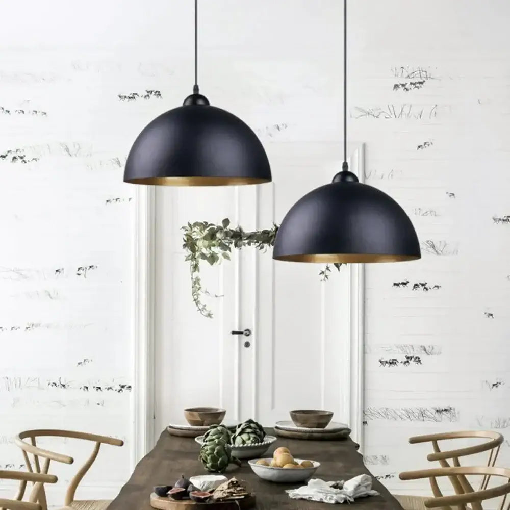 Industrial black and gold metal cage pendant light with black metal cage and gold-trimmed interiors above dining table
