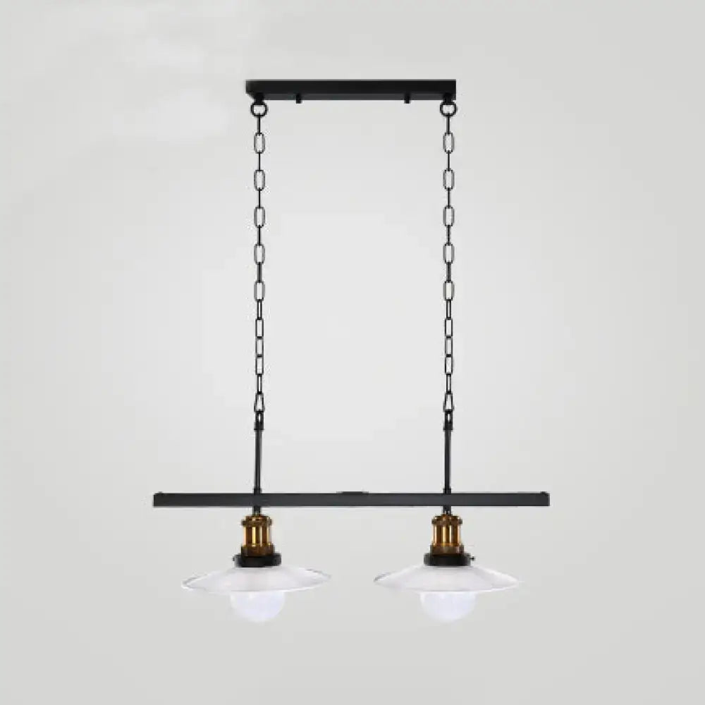 Black metal pendant light fixture with two clear glass shades and brass accents for kitchen island lighting