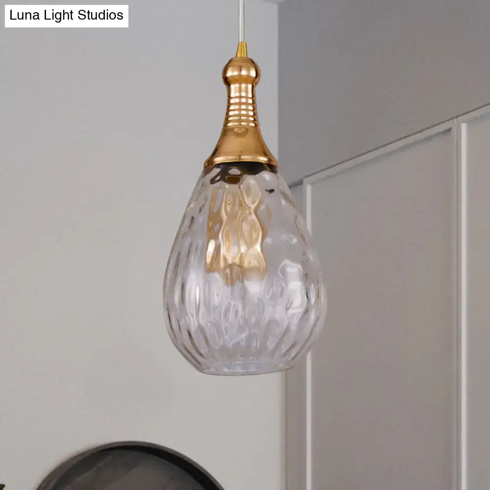 A clear teardrop-shaped glass ceiling light with hammered finish and gold-toned top in decorbites daisy industrial black brass style