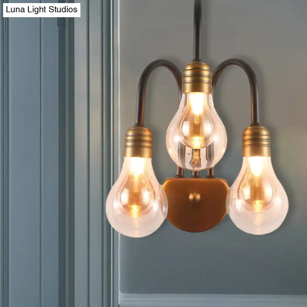 Industrial black and brass wall lamp with three glowing incandescent bulbs 220v-240v mounted on wooden backplate