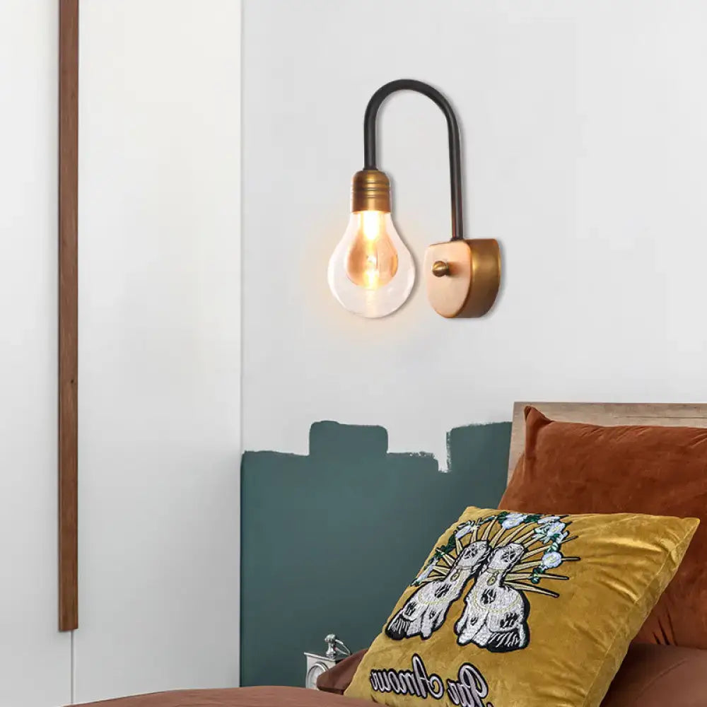 Industrial black and brass wall lamp with exposed filament bulb and curved arm suitable for bedroom light fixture