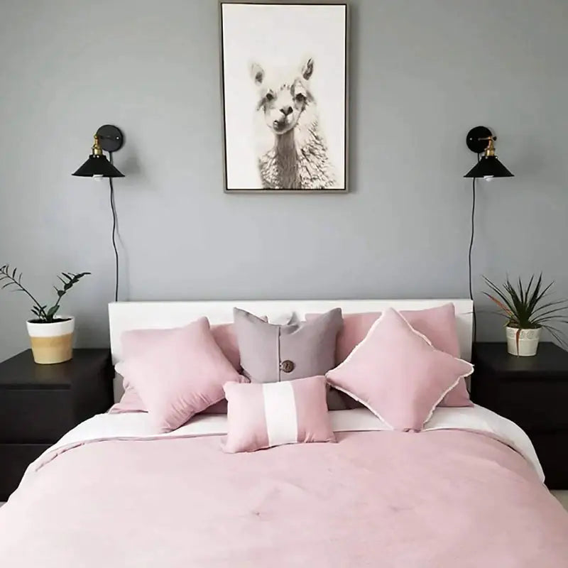 A cozy bed with soft pink bedding and blush pillows illuminated by decorbites industrial black wall lamp